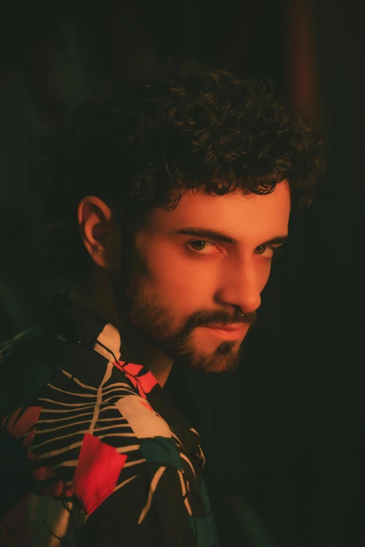 a man with curly hair wearing a floral shirt, an album cover, inspired by Alexis Grimou, looking away from camera, hasan piker, portrait image, metzinger