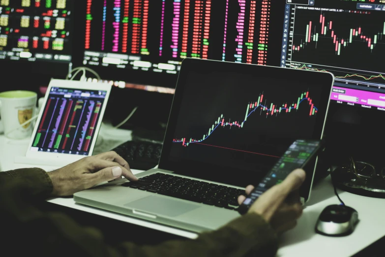 a man sitting at a desk using a laptop computer, pexels, analytical art, displaying stock charts, paul barson, square, multicoloured