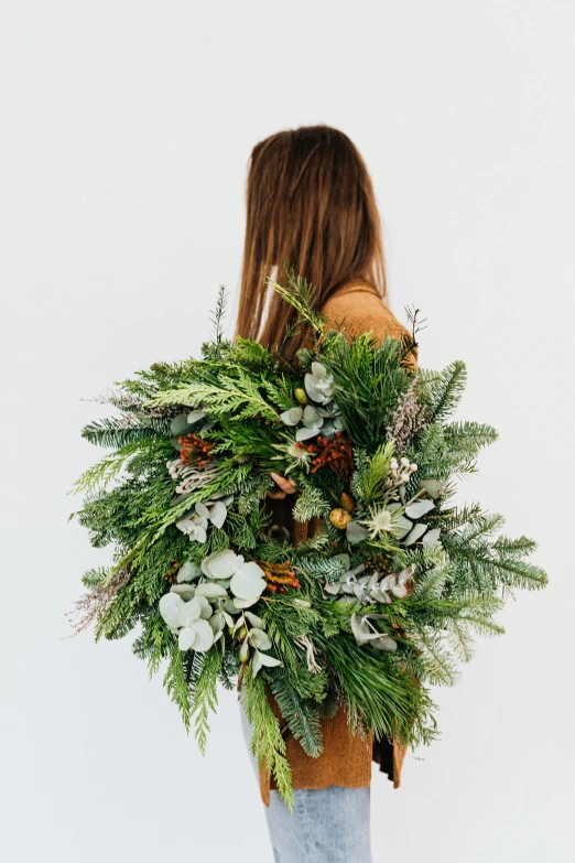 a woman holding a large bouquet of greenery, by Jessie Algie, organic ornaments, throw, backfacing, lush