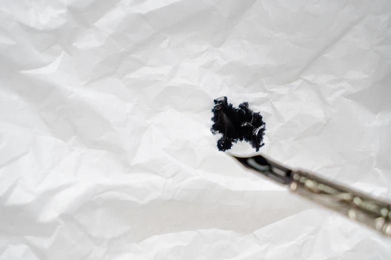 a toothbrush sitting on top of a piece of paper, an ink drawing, by Adam Marczyński, unsplash, visual art, black paint drops, paper crumpled texture, set against a white background, an artistic pose