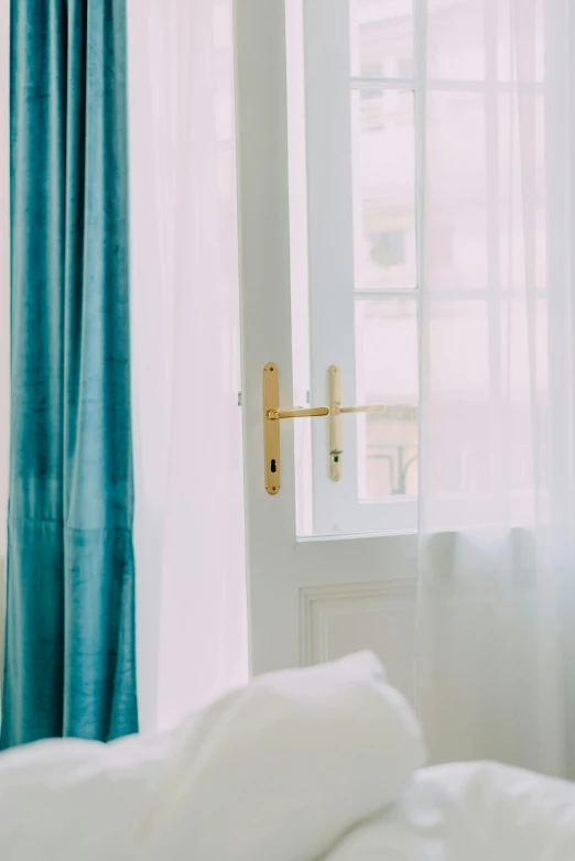 a white bed sitting in a bedroom next to a window, by Anna Haifisch, unsplash, cyan and gold scheme, doorway, curtain, morning detail