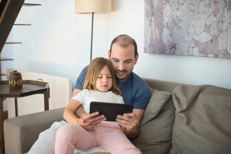 a man and a little girl sitting on a couch, pexels, programming, handheld, rectangle, spanish