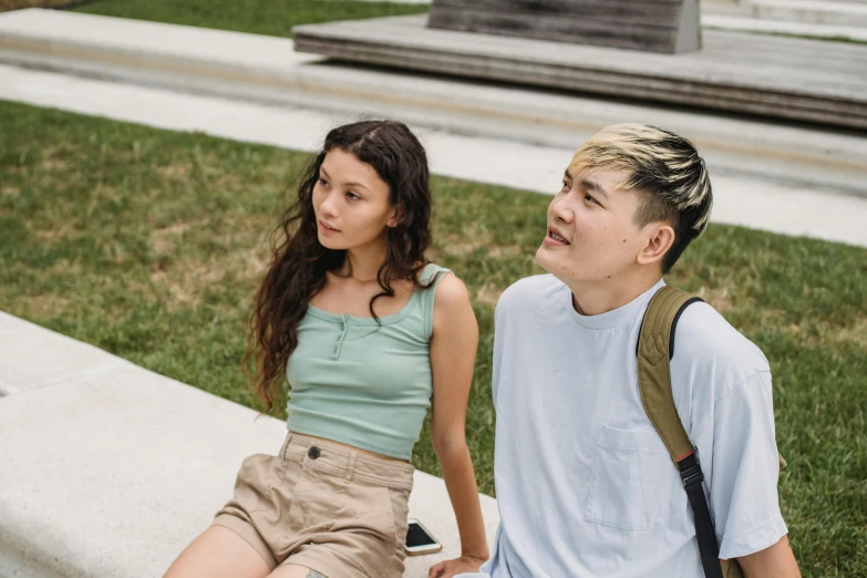 a couple of young people sitting next to each other, trending on pexels, realism, dressed in a top and shorts, asian descend, looking off to the side, guide