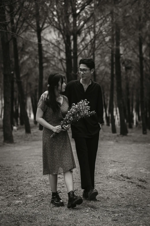 a man and woman standing next to each other in a forest, a black and white photo, by Yosa Buson, unsplash, realism, carrying flowers, medium format. soft light, 256435456k film, dang my linh