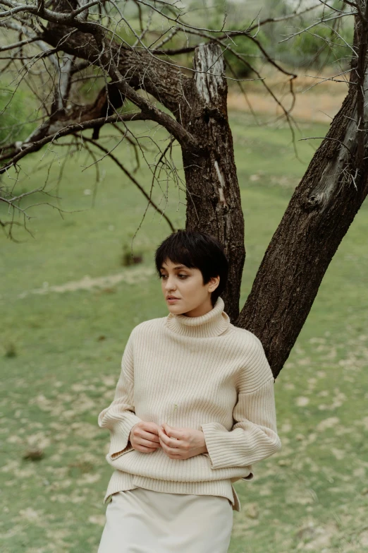 a woman standing next to a tree in a field, an album cover, by Winona Nelson, in white turtleneck shirt, pixie cut, medium format. soft light, chilean