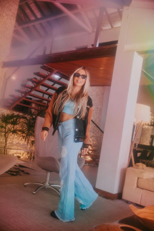 a woman standing in a living room next to a staircase, an album cover, inspired by Károly Lotz, instagram, happening, with sunglass, wearing a crop top, with very long blonde hair, wearing double denim