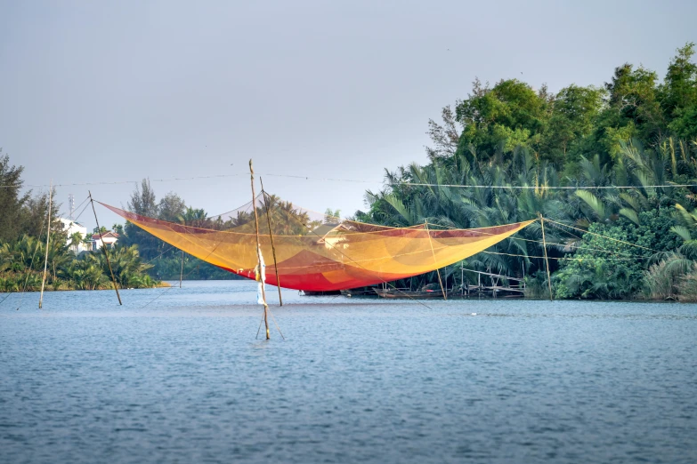 a red and yellow hammock sitting on top of a body of water, gutai group, phuoc quan, nets, panoramic view, lpoty