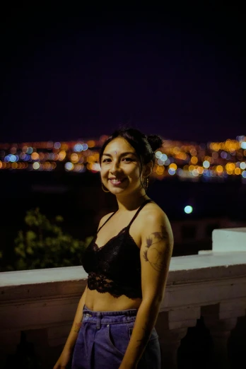 a woman standing on top of a balcony at night, wearing shipibo tattoos, bralette, low quality photo, portrait image