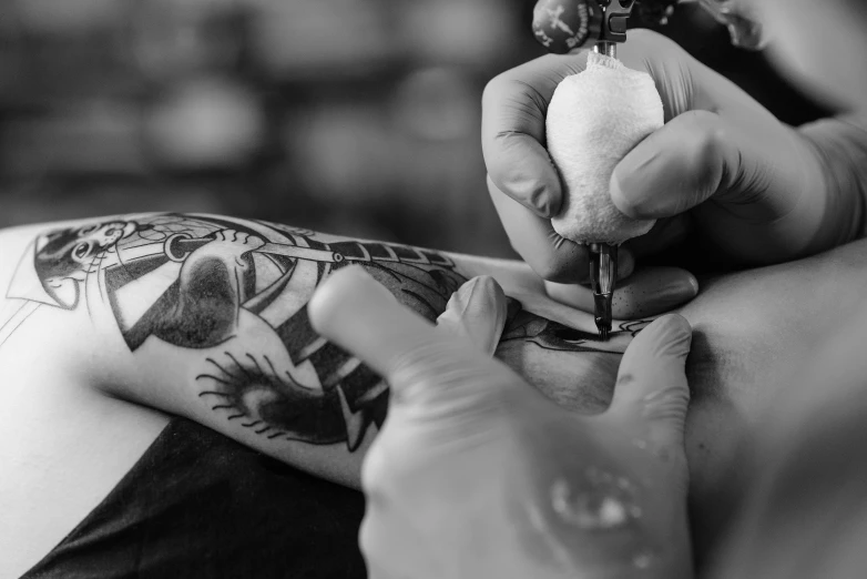 a man getting a tattoo on his arm, a tattoo, by Adam Marczyński, pexels, process art, black and white coloring, technologies, bird tattoo, bodypainting