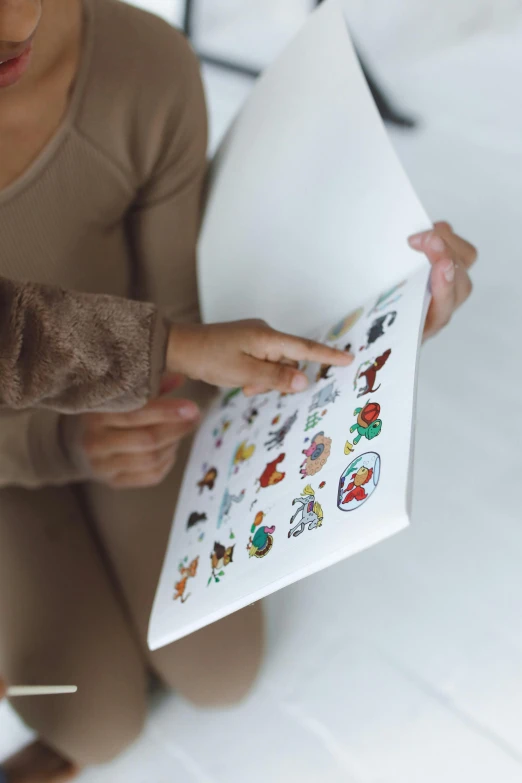 a little girl sitting on a bed reading a book, a cartoon, by Nina Hamnett, process art, unused sticker sheet, emoji, on a white table, medium close up shot