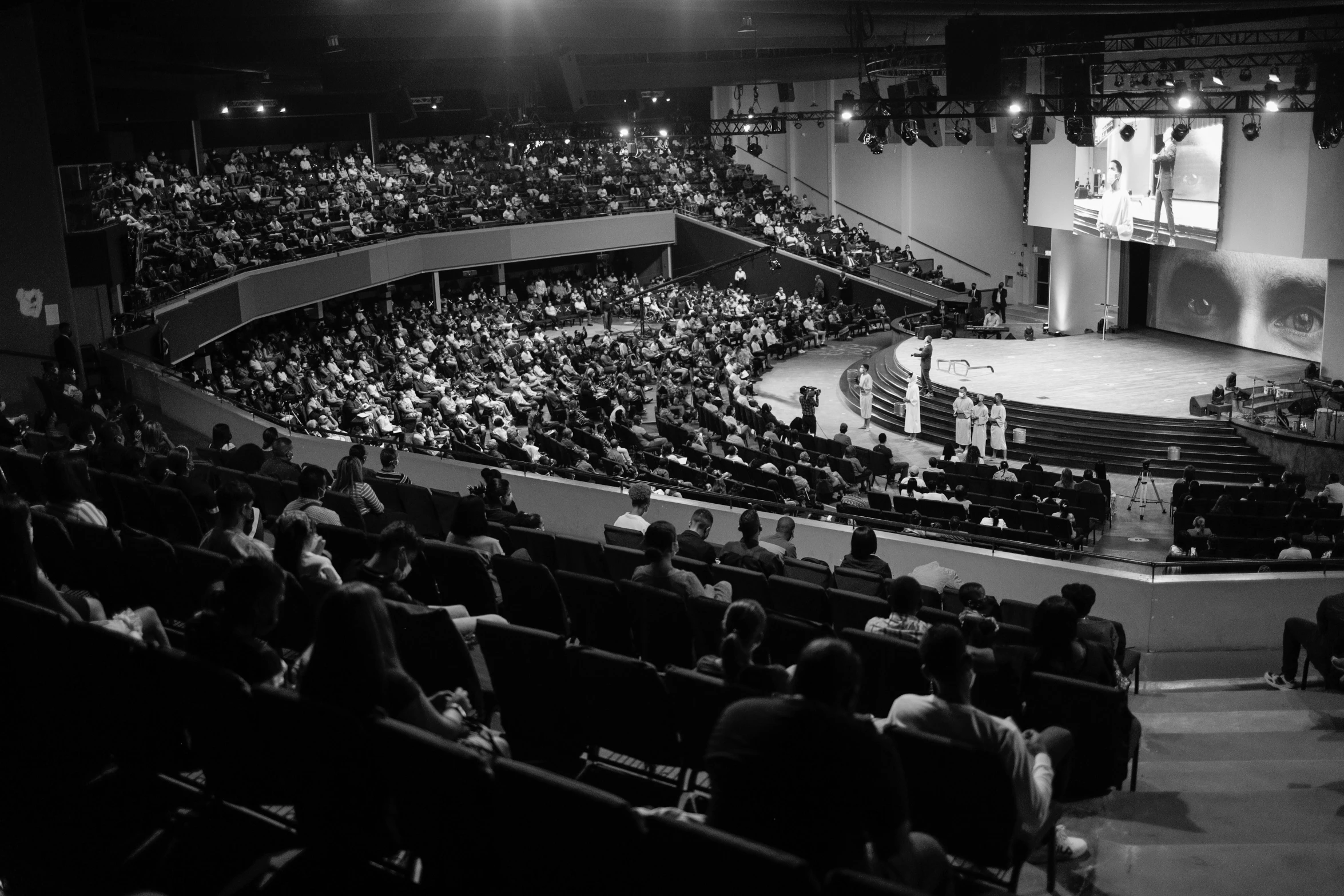 a black and white photo of an auditorium full of people, by Adam Chmielowski, kenneth copeland, sparsely populated, jon macnair, circle pit