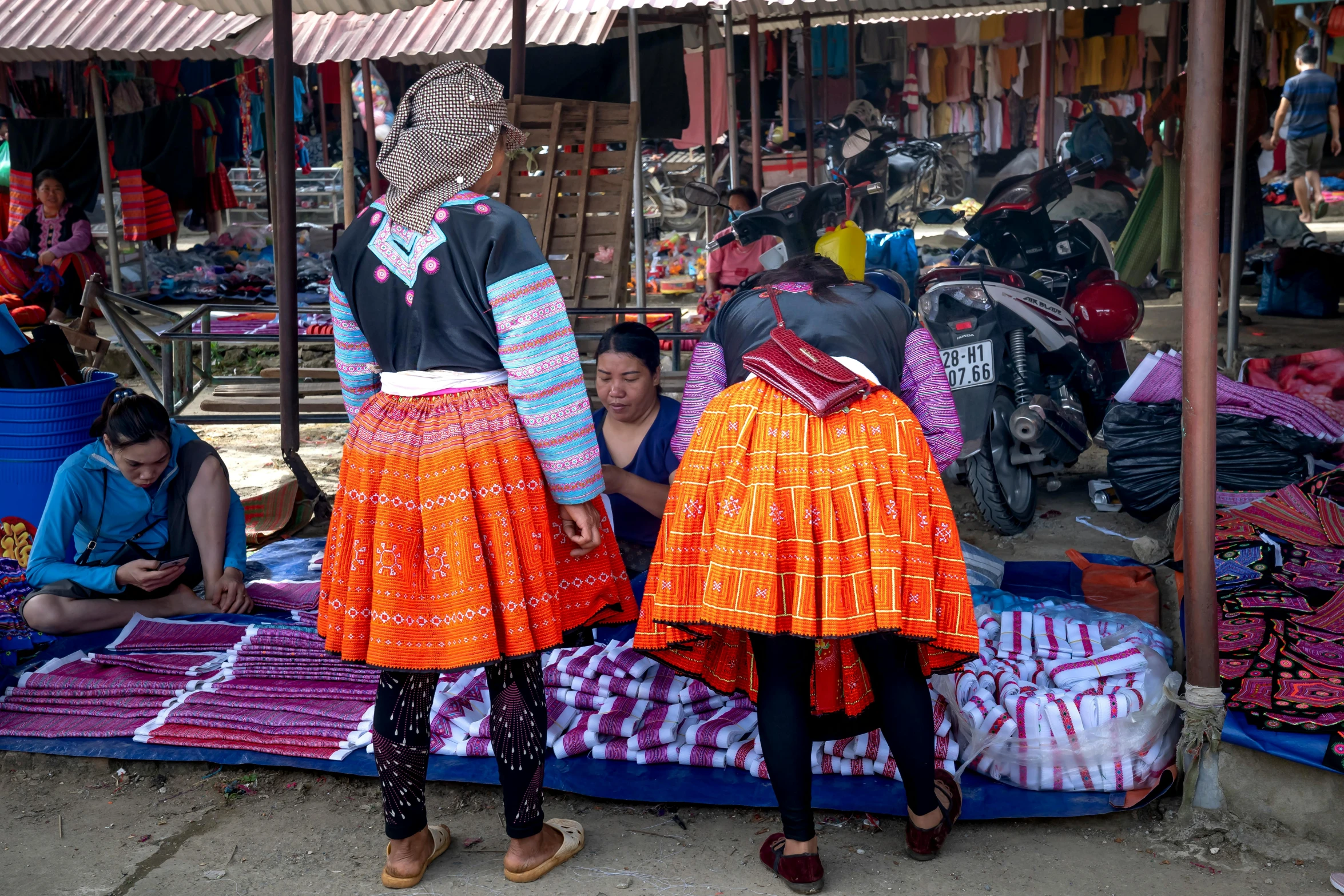 a couple of women standing next to each other, happening, in style of lam manh, textiles, photo taken from behind, square