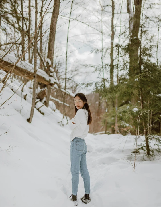 a woman standing in the snow in the woods, inspired by Asher Brown Durand, unsplash contest winner, wearing jeans, a young asian woman, 😭 🤮 💕 🎀, 8k octan photo