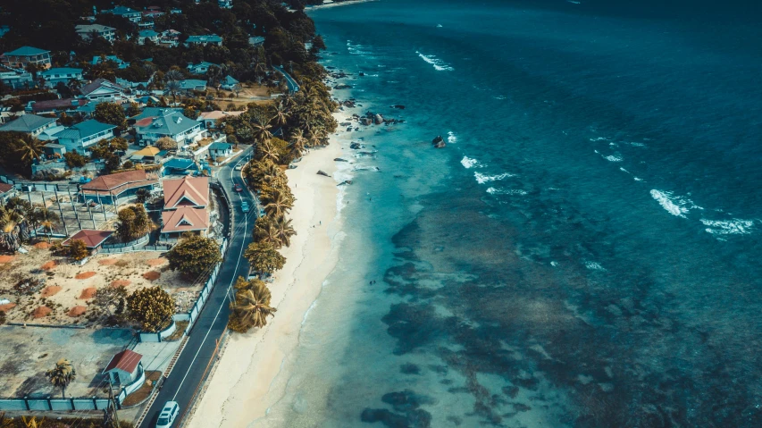 a large body of water next to a beach, a screenshot, pexels contest winner, helicopter view, reunion island, beachfront mansion, road to the sea