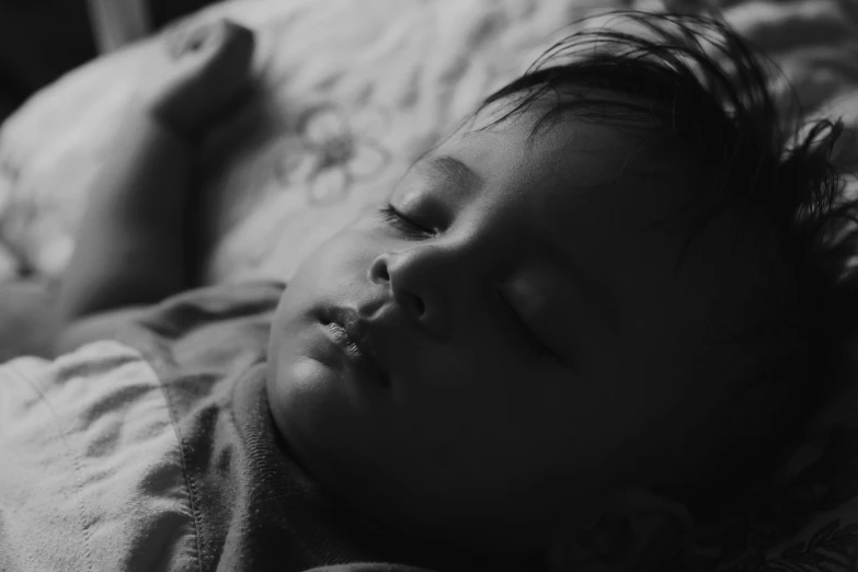 a black and white photo of a baby sleeping on a bed, a black and white photo, pexels contest winner, hurufiyya, soft light.4k, with accurate face, in the evening, monochrome:-2