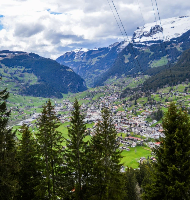 a view of a town from the top of a mountain, by Julia Pishtar, pexels contest winner, renaissance, lauterbrunnen valley, lush green, skiing, snow capped mountains