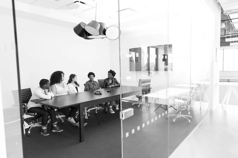 a group of people sitting around a table, a black and white photo, by Gavin Hamilton, pexels, clear glass wall, afro tech, photograph of 3d ios room, panel of black