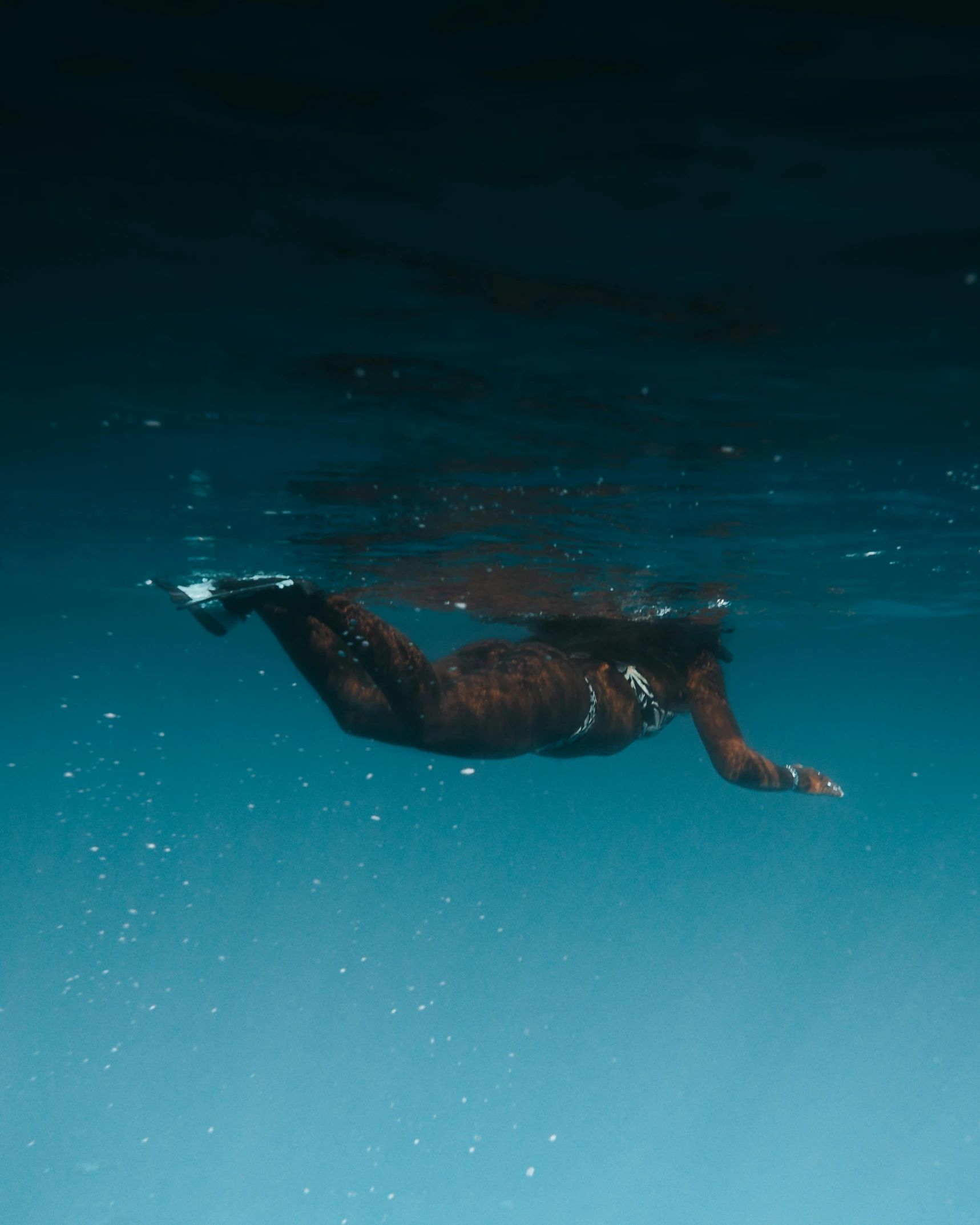 a person swimming in a body of water, bottom of ocean, dark skinned, from below, trending photo