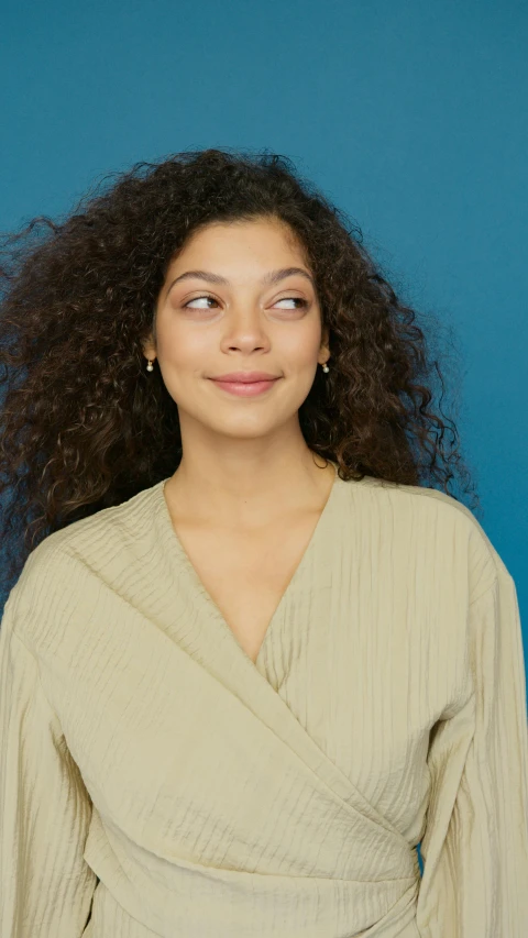 a woman with curly hair posing for a picture, wear's beige shirt, wearing nanotech honeycomb robe, portrait top light, teal