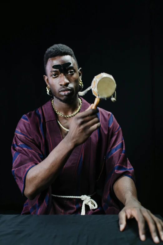 a man holding a mirror in front of his face, an album cover, inspired by Theo Constanté, trending on unsplash, afrofuturism, wearing an african dress, actor, mkbhd, a human bard