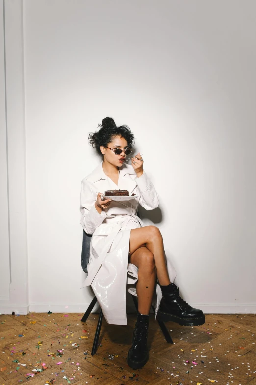 a woman sitting in a chair reading a book, an album cover, pexels contest winner, visual art, white outfit, eating cakes, wearing black boots, woman in streetwear