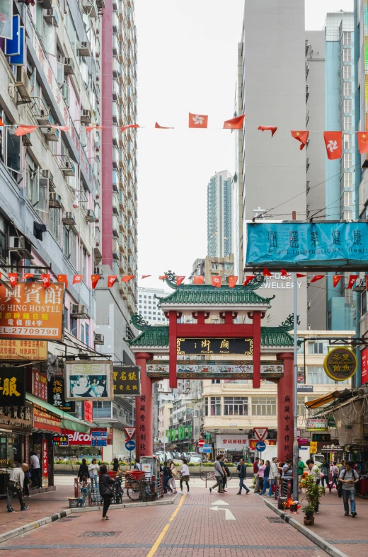 a group of people walking down a street next to tall buildings, chinese architecture, street signs, archway, storefronts