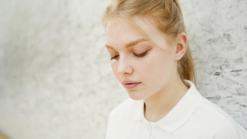 a young girl leaning against a wall with her eyes closed, a character portrait, by Emma Andijewska, trending on pexels, round jawline, natural soft pale skin, close up of a blonde woman, soft chin