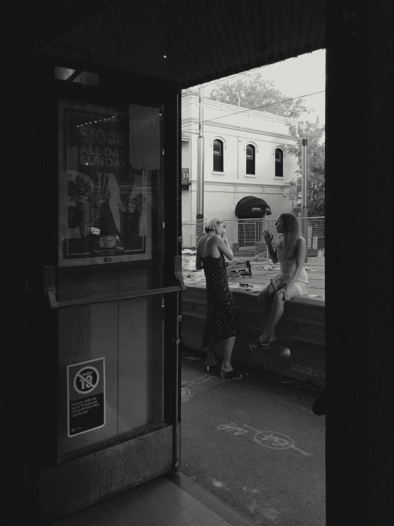 a couple of people standing outside of a building, a black and white photo, happening, inside a bar, on a hot australian day, about to enter doorframe, taken in the late 2010s