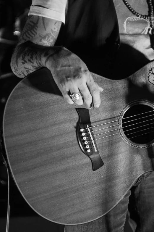 a black and white photo of a man playing a guitar, unsplash, tattooed, exactly 5 fingers, epk, western setting