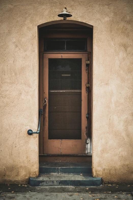 a red fire hydrant sitting in front of a door, by Lee Loughridge, unsplash, postminimalism, muted brown, pueblo architecture, 1848, metal framed portal