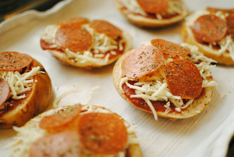 a tray of mini pizzas with pepperoni and cheese, by Joe Bowler, pexels, eating garlic bread, thumbnail, steamed buns, bottom body close up