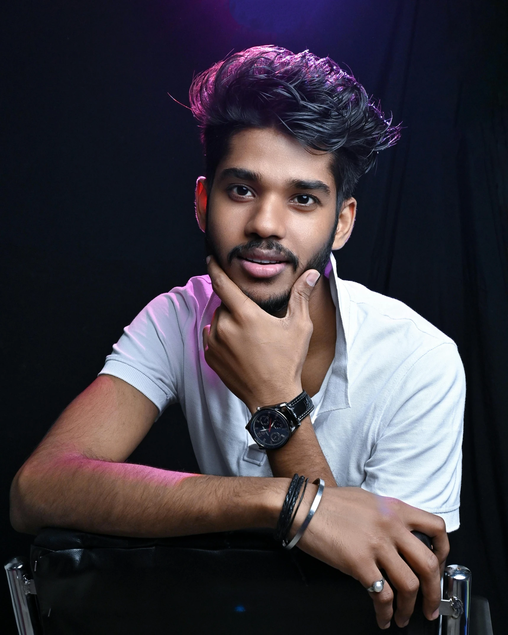 a man sitting in a chair with his hand on his chin, by Max Dauthendey, trending on unsplash, hurufiyya, androgynous face, indian, lovingly looking at camera, bisexual lighting