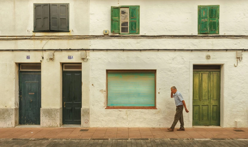 a man walking down a sidewalk in front of a building, inspired by Josep Rovira Soler, pexels contest winner, hyperrealism, green, old house, photo for a store, in a square