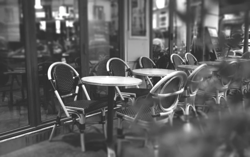 a black and white photo of tables and chairs, a black and white photo, by Daniel Gelon, pexels, paris 2010, coffee, photo on iphone, bokeh. i