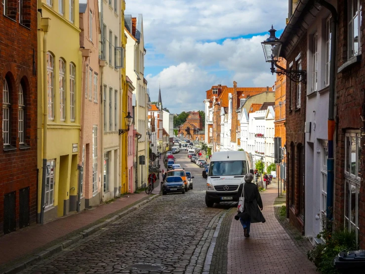 a woman is walking down a cobblestone street, by Tobias Stimmer, pexels contest winner, renaissance, lower saxony, white buildings with red roofs, thumbnail, seaside