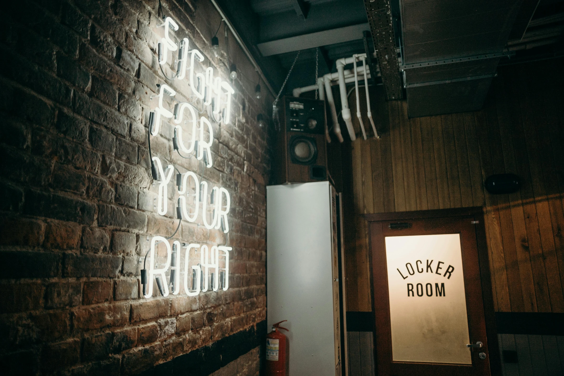 a room with a brick wall and a neon sign, pexels contest winner, getting ready to fight, left right front back, lightweight, indoor light