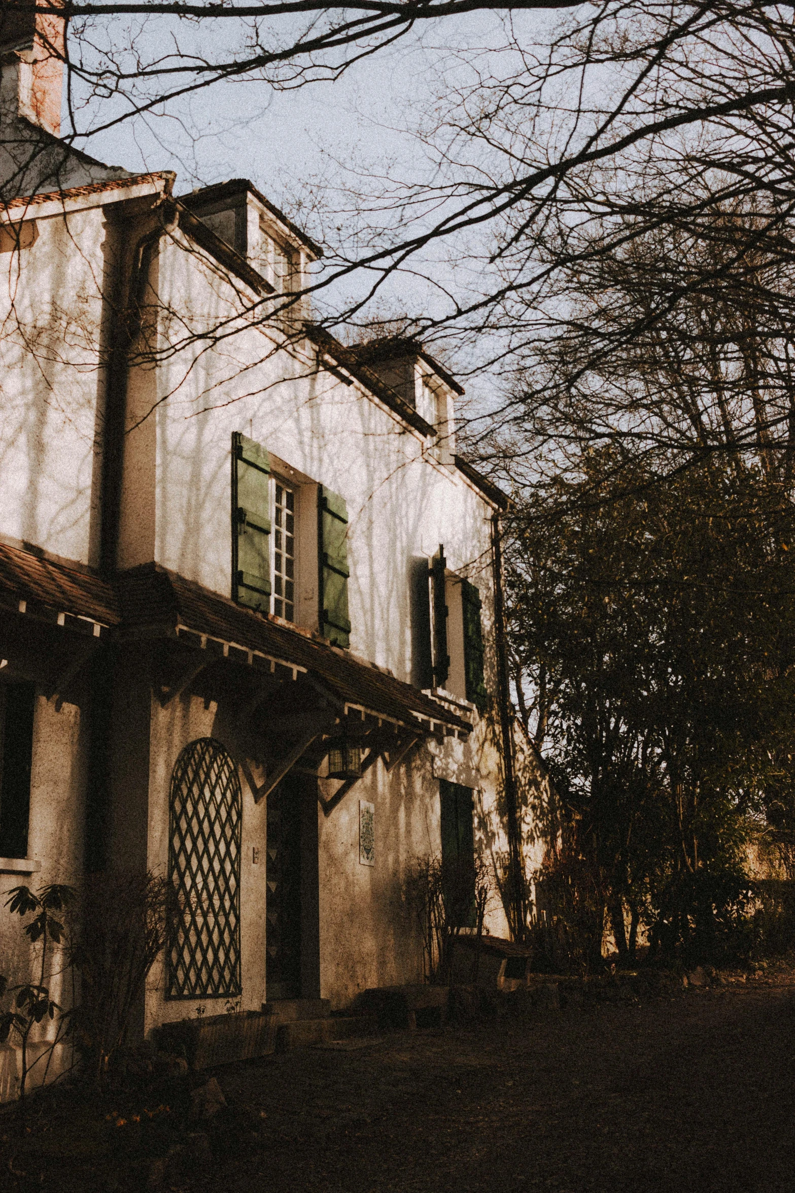 a building with a clock on the top of it, an album cover, inspired by Jean-Baptiste-Camille Corot, backyard, old color photograph, afternoon sunlight, spooky mansion