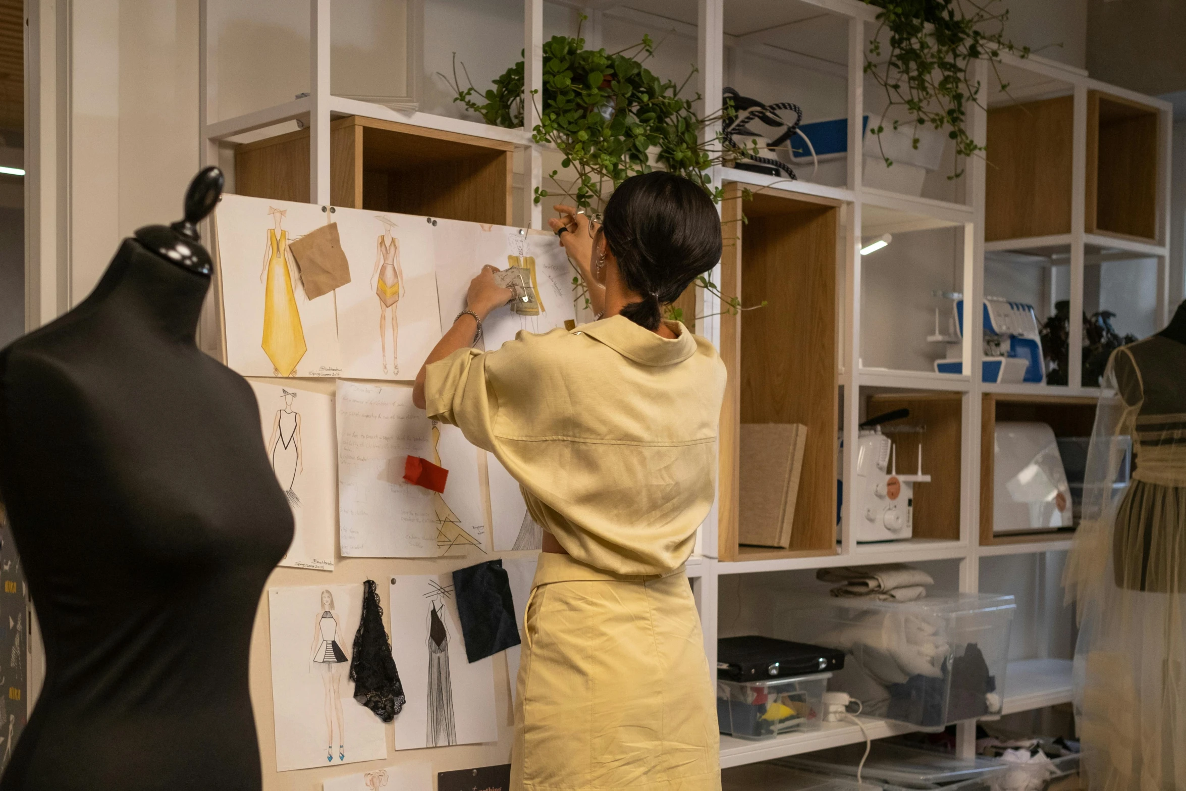 a woman standing next to a mannequin in a room, process art, working in an office, white and yellow scheme, sustainable materials, avatar image
