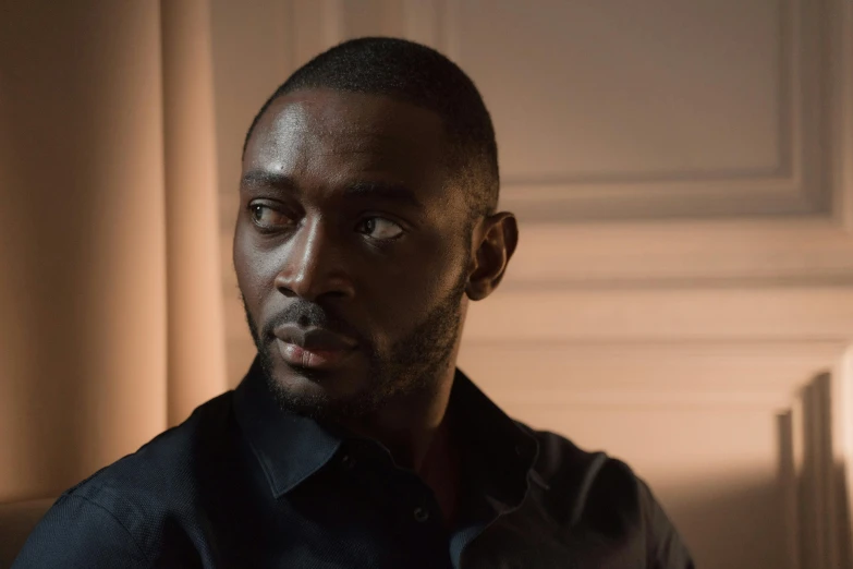 a man in a black shirt sitting on a couch, an album cover, inspired by Theo Constanté, pexels contest winner, serial art, mkbhd, cinematic close-up bust shot, standing in a dimly lit room, looking to his side