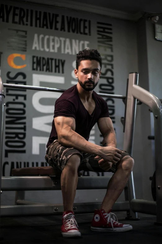 a man sitting on a bench in a gym, by Ismail Acar, confident stance, nivanh chanthara, profile image, fit pic