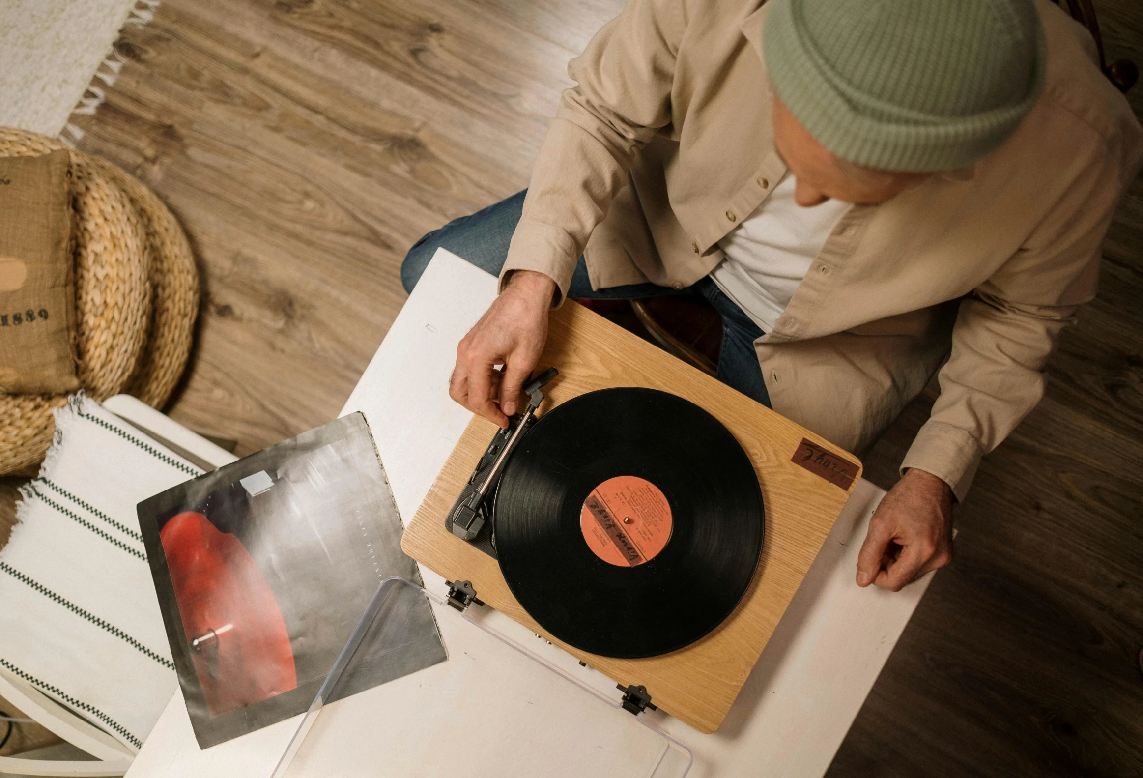 a man sitting at a table with a record in front of him, an album cover, trending on pexels, on a wooden tray, detailed product image, turntables, hammershøi