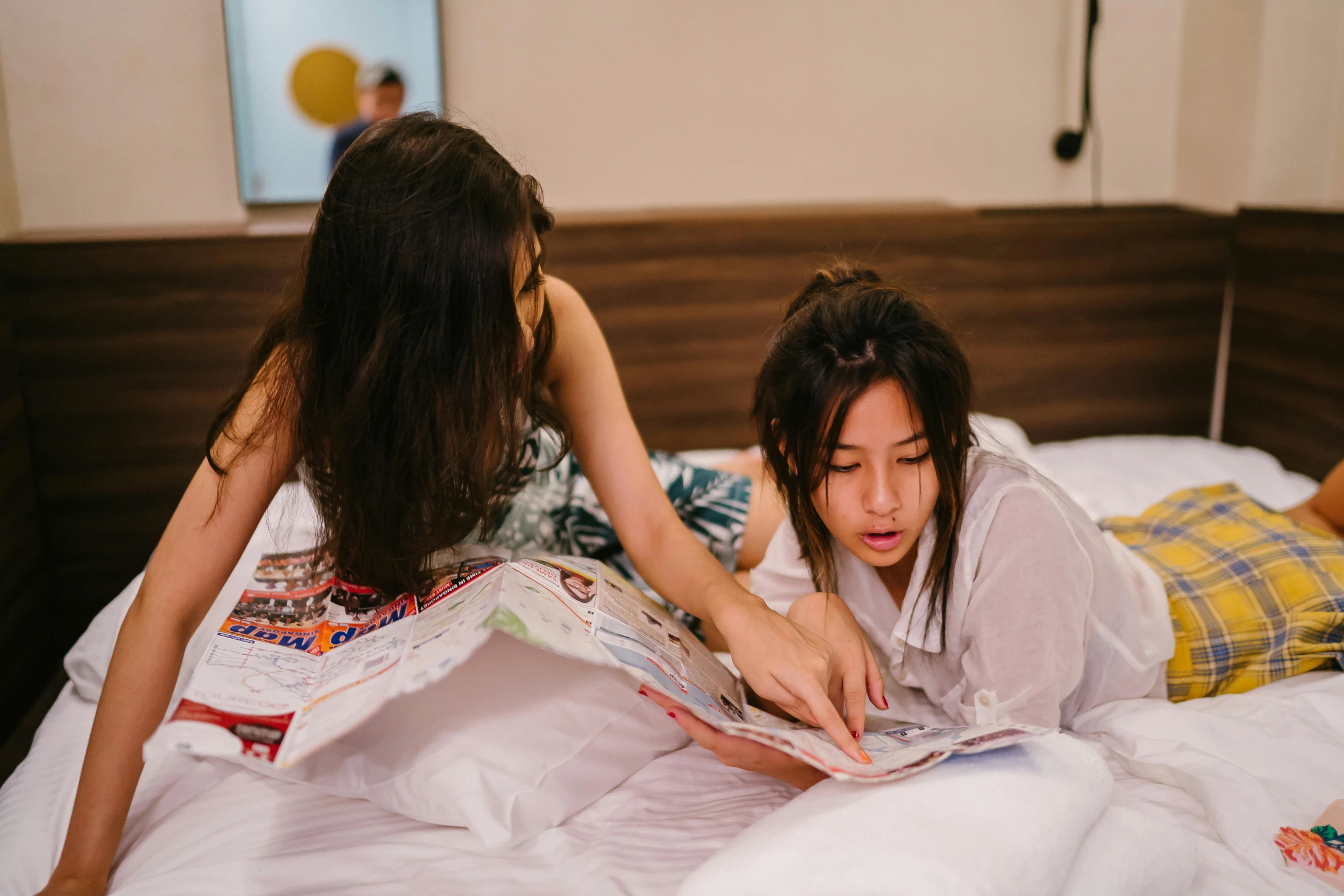 a couple of women laying on top of a bed, pexels contest winner, studious, gemma chen, reading a newspaper, walking down