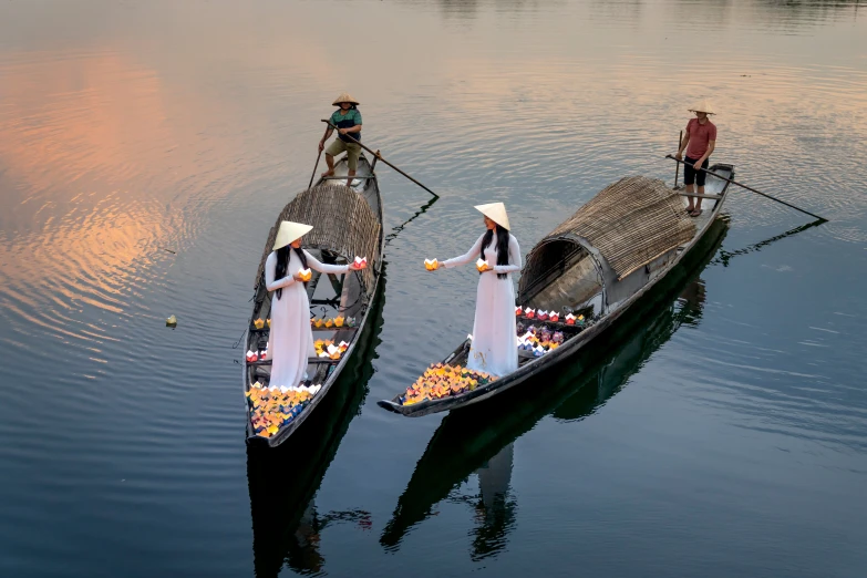 a couple of boats that are sitting in the water, inspired by Steve McCurry, pexels contest winner, conceptual art, ao dai, two hovering twin nuns, vendors, evening light