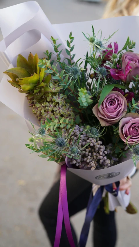 a close up of a person holding a bunch of flowers, by Rachel Reckitt, purple and green, flower shop scene, no cropping, thistle