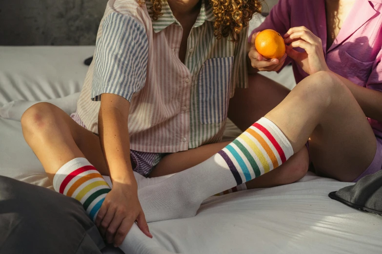 a couple of women sitting on top of a bed, inspired by Okuda Gensō, trending on pexels, striped socks, multicoloured, environmental shot, alternate angle