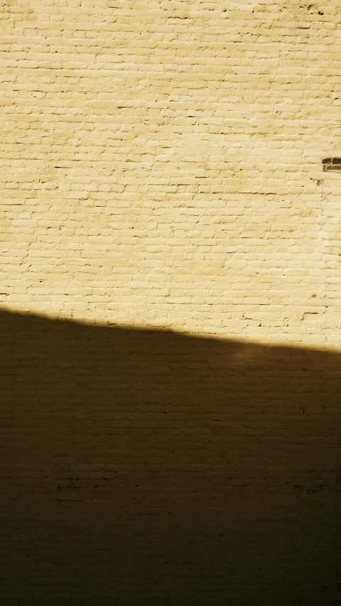 a red fire hydrant sitting on top of a sidewalk, a picture, inspired by Agnes Martin, unsplash, postminimalism, light - brown wall, contre jour, brick wall texture, on a yellow canva