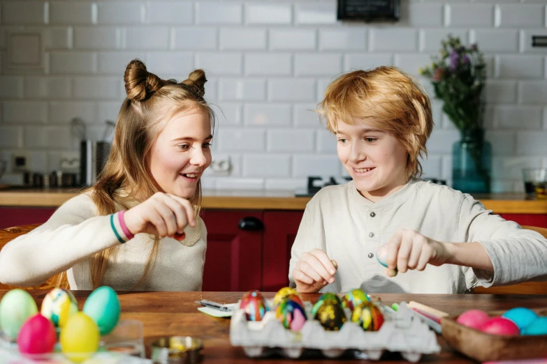 a couple of young girls sitting at a table, by Joe Bowler, pexels contest winner, happening, holding easter eggs, avatar image, cute boys, preparing to fight