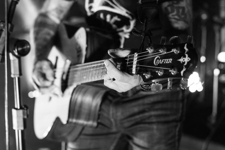 a black and white photo of a person playing a guitar, by Matt Cavotta, tattooed, facebook photo, detail shot, uploaded