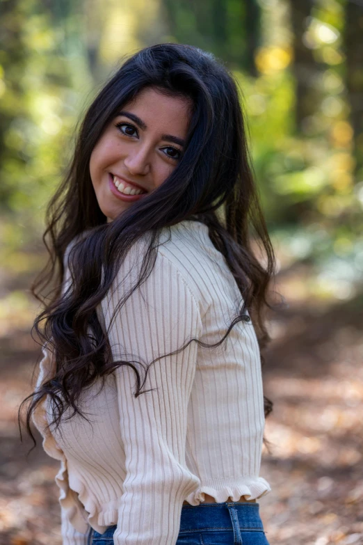 a woman posing for a picture in the woods, wavy long black hair, ((portrait)), young middle eastern woman, smiling sweetly