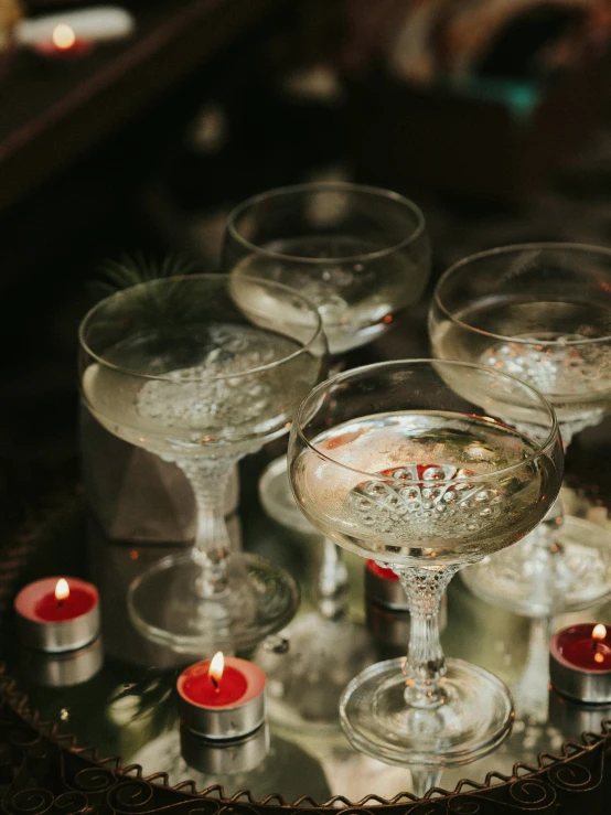 a group of wine glasses sitting on top of a table, bubbly, with a drink, candles, vintage aesthetic